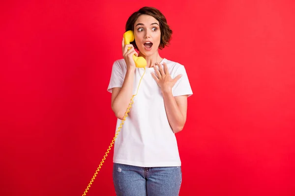 Portré szép csodálkozó vidám lány beszél telefonon megvitatása hírek elszigetelt felett élénk piros színű háttér — Stock Fotó