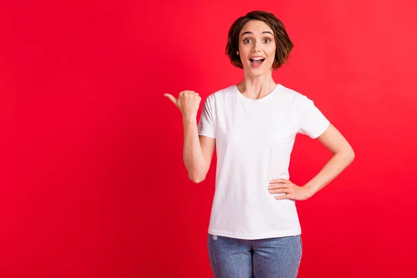 Retrato de menina alegre surpreendente atraente demonstrando espaço de cópia anúncio novidade isolado sobre fundo de cor vermelha brilhante — Fotografia de Stock