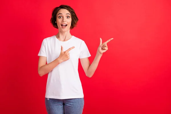 Retrato de atraente menina alegre espantado demonstrando nova novidade oferta anúncio isolado sobre fundo de cor vermelha brilhante — Fotografia de Stock