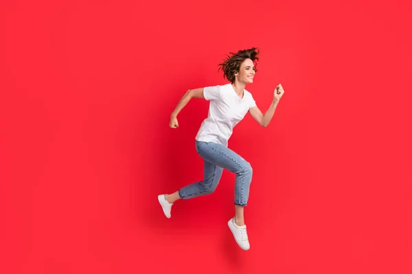 Tamanho do corpo de comprimento total vista de atraente motivado alegre menina saltando correndo rápido isolado sobre fundo de cor vermelha brilhante — Fotografia de Stock