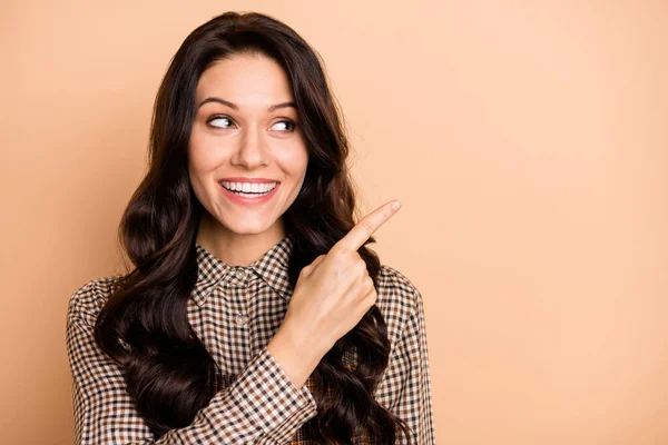 Porträtt av ganska glada vågiga hår flicka visar kopiera utrymme välja val annons isolerad över beige pastell färg bakgrund — Stockfoto