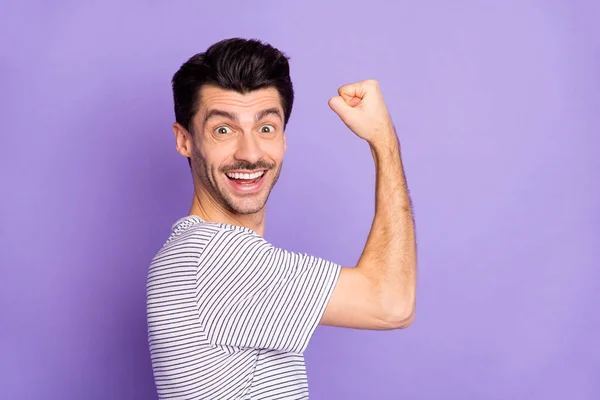 Foto de feliz animado sorrindo alegre louco homem mostrando bíceps músculos poderoso isolado no fundo cor violeta — Fotografia de Stock