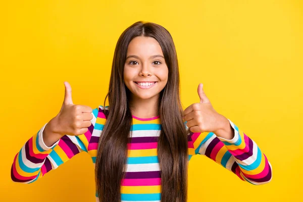 Foto de menina levantar dois polegares até o sorriso brilhante usar camisa listrada isolado cor amarela fundo — Fotografia de Stock