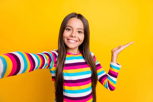 Foto de menina tomar selfie braço segurar espaço vazio usar camisa listrada isolado cor amarela fundo — Fotografia de Stock