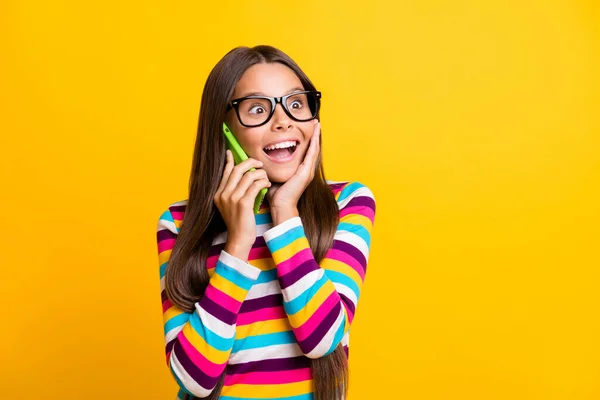 Retrato fotográfico de una chica sorprendida hablando por teléfono celular mirando el espacio de copia tocando la mejilla aislada sobre un fondo de color amarillo brillante — Foto de Stock