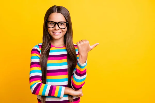 Retrato fotográfico de una colegiala alegre apuntando a un espacio en blanco con gafas con el dedo sonriente aislado color amarillo vibrante fondo —  Fotos de Stock