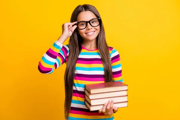 Fénykép portré boldog mosolygós iskolás lány tartása tankönyvek érintő szemüveg elszigetelt élénk sárga színű háttér — Stock Fotó