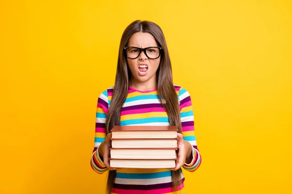 Foto retrato de menina irritada mantendo livros sorridentes não quer fazer lição de casa isolado no fundo cor amarela vibrante — Fotografia de Stock