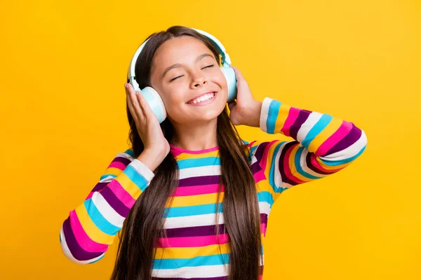 Portret uczennicy słuchającej muzyki ze słuchawkami zamkniętymi oczami uśmiechniętymi radośnie odizolowanymi na jasnożółtym tle — Zdjęcie stockowe