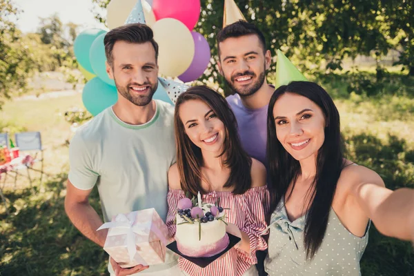 Zdjęcie atrakcyjne kobiety i mężczyźni zrobić selfie aparat trzymać tort urodzinowy obecny uśmiech na zewnątrz w ogródku — Zdjęcie stockowe