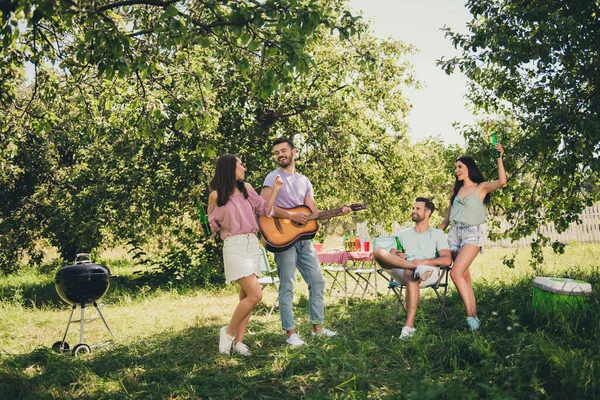 Pozitif çiftlerin tam vücut fotoğrafı piknik şişesi, bira şişesi hafta sonu dışarıda gitar çalmak dışarıda arka bahçede. — Stok fotoğraf