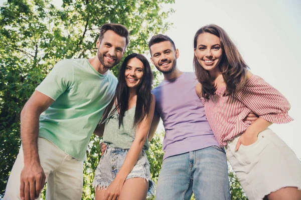 Vista de ángulo bajo foto de cuatro hombres y mujeres atractivas abrazarse unos a otros amigos radiante sonrisa feliz descanso en el parque al aire libre — Foto de Stock