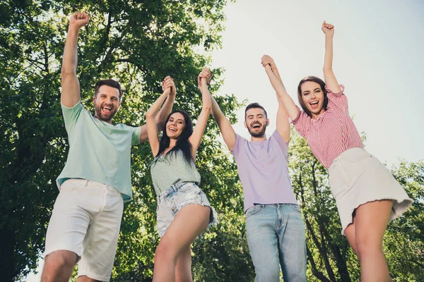 Vista de ángulo bajo foto de los hombres y mujeres de pelo castaño feliz sostener levantar las manos puños ganador vacaciones gratis verano al aire libre —  Fotos de Stock