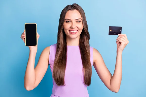 Фотопортрет щасливої красивої дівчини, що показує сенсорний екран смартфона копія банківської кредитної картки ізольовано на яскраво-блакитному фоні — стокове фото