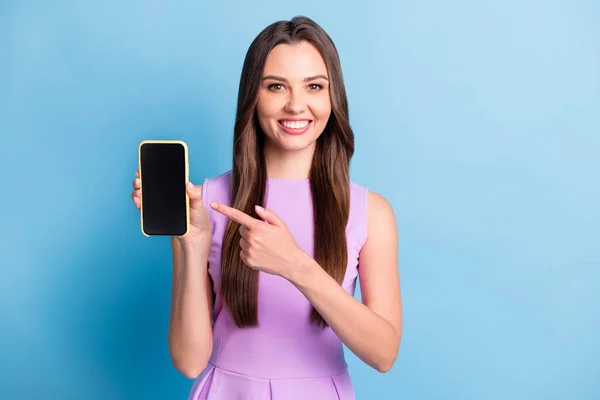 Retrato fotográfico de la joven sonriente apuntando a la pantalla del teléfono inteligente espacio en blanco aislado en el fondo de color azul brillante — Foto de Stock