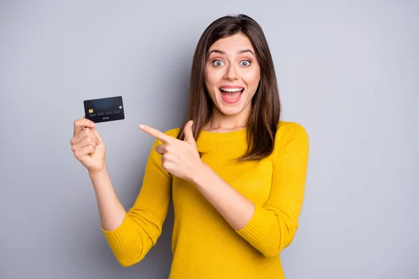 Portret van vrij verbaasd blij vrolijk meisje houden in handen demonstreren bankkaart nieuwigheid geïsoleerd over grijze kleur achtergrond — Stockfoto