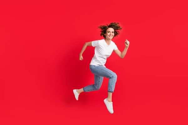 Tamanho do corpo de comprimento total vista de menina alegre atraente pulando ação em execução isolado sobre fundo de cor vermelha brilhante — Fotografia de Stock