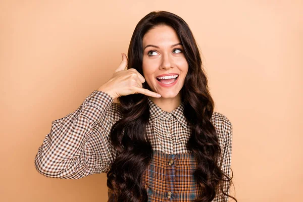 Photo de jeune fille attrayante sourire heureux montrer doigts signe d'appel parler regarder espace vide isolé sur fond de couleur beige — Photo