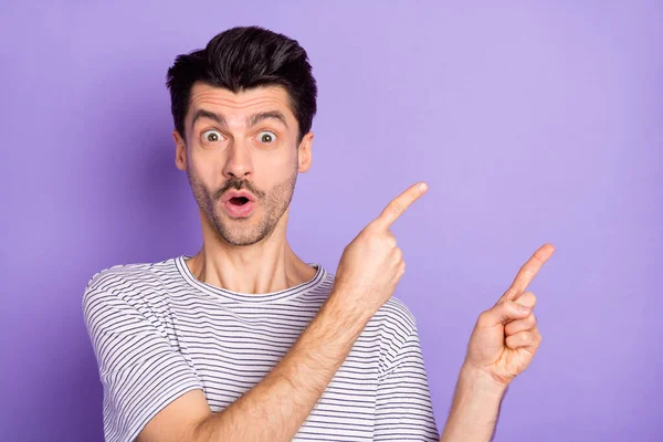 Foto van geschokte man directe vinger lege ruimte open mond dragen wit gestreept t-shirt geïsoleerde violette achtergrond — Stockfoto