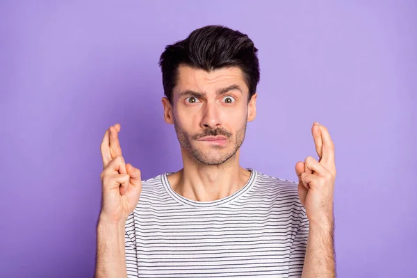 Foto von nervösen Kerl gekreuzten Daumen beißen Lippe Look Kamera tragen schwarz gestreifte T-Shirt isoliert lila Hintergrund — Stockfoto