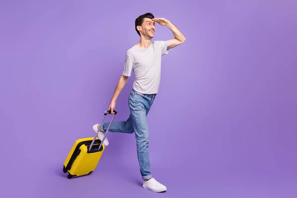 Фото взволнованного парня, держащего кейс ладонь лоб выглядит пустым пространство носить футболки джинсы кроссовки изолированный фиолетовый фон — стоковое фото