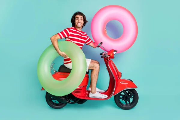 Perfil vista lateral de chico alegre guapo conduciendo ciclomotor llevar boya aislado sobre fondo de color turquesa verde brillante —  Fotos de Stock