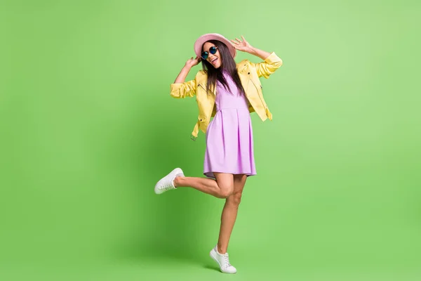 Foto de chica bastante funky disfrutar de baile de fin de semana desgaste chaqueta amarilla vestido violeta zapatillas de deporte gorra rosa aislado color verde fondo — Foto de Stock