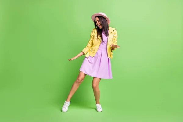 Foto av ganska bedårande flicka vårdslös dans bära gul jacka lila klänning rosa huvudbonader skor isolerad grön färg bakgrund — Stockfoto