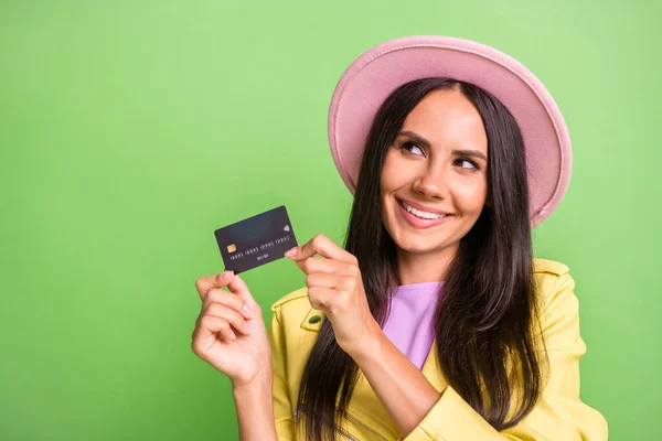 Photo of dreamy girl hold plastic debit card look empty space wear yellow jacket pink headwear isolated green color background — Stock Photo, Image