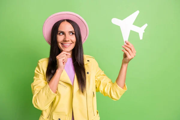 Foto portret van nieuwsgierige vrouw glimlachend denken over reis vliegtuig vakanties in roze hoed geïsoleerd op levendige groene kleur achtergrond — Stockfoto