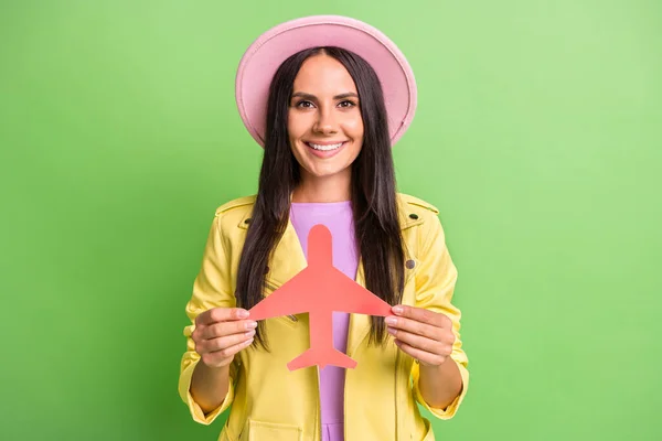 Foto retrato de mulher sorrindo feliz sorrindo mantendo plano de papel em chapéu rosa isolado no fundo de cor verde vibrante — Fotografia de Stock