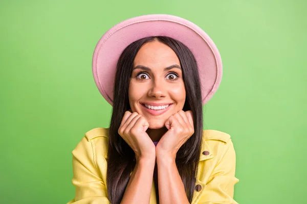 Foto portret van gekke nieuwsgierige brunette vrouw staren aanraken wangen dragen hoed geïsoleerd op fel groene kleur achtergrond — Stockfoto