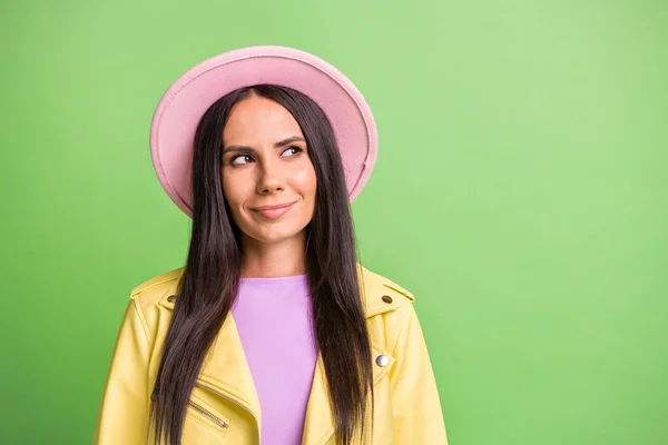 Foto portret van nieuwsgierige brunette op zoek naar lege ruimte dragen hoed jas geïsoleerd op fel groene kleur achtergrond — Stockfoto