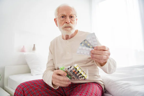 老年养恤金领取者不高兴、悲伤、不健康、卧床不舒服的照片选择药丸止痛药 — 图库照片