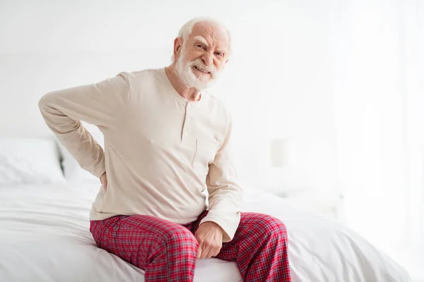 老年人忧心忡忡的照片手扶着脊柱疼痛痉挛症坐在糟糕的家庭休息保健上 — 图库照片