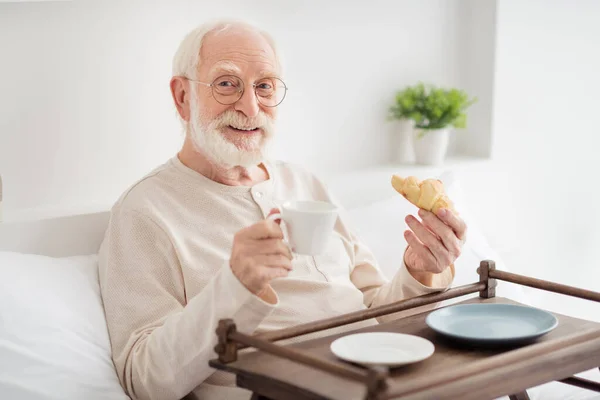 高齢者の年金受給者の写真幸せな肯定的な悪い家庭飲料茶で朝の朝食を楽しむクロワッサンを食べる — ストック写真