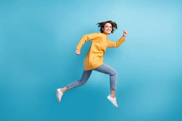 Full length body side profile photo of female runner smiling cherfully jumping high isolated on vivid blue color background — ストック写真