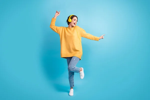 Foto de cuerpo entero de estudiante en jersey de auriculares cantando bailando felizmente aislado sobre fondo de color azul brillante —  Fotos de Stock