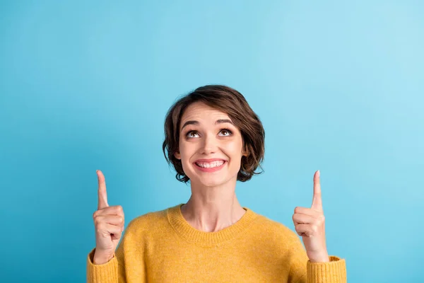 Foto porträtt av roliga glada flicka med bob frisyr pekar upp på copyspace leende isolerad på klarblå färg bakgrund — Stockfoto