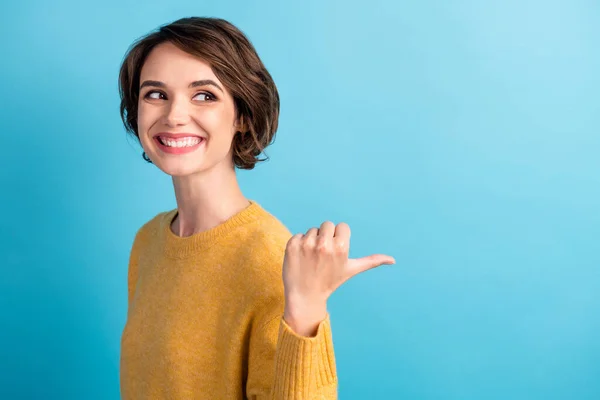 Фотопортрет смішної допитливої дівчини в пуловері, що показує на порожньому просторі з палець посміхається ізольовано на яскраво-блакитному фоні — стокове фото