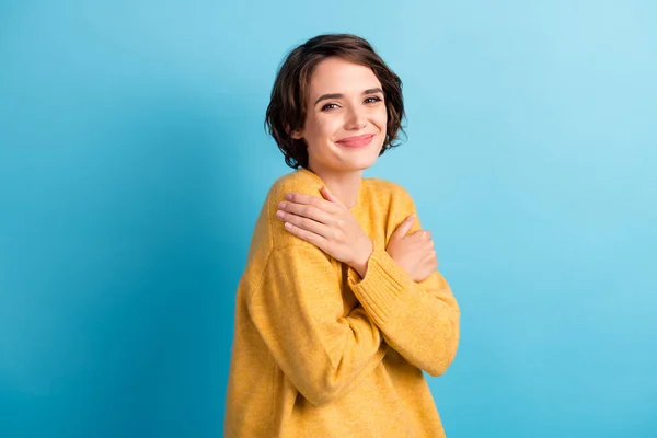 Foto retrato de menina bonito abraçando-se usando jumper amarelo quente isolado no fundo de cor azul vibrante — Fotografia de Stock