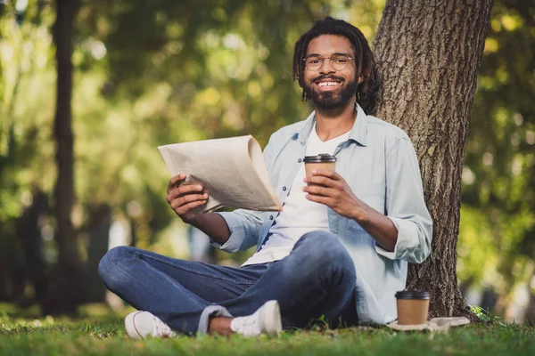 Foto retrato de homem de óculos sorrindo sentado no parque verde sob árvore bebendo cofee ler jornal — Fotografia de Stock