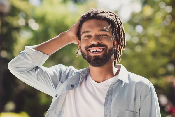 Photo de charmante belle brune peau foncée homme porter chemise en denim tenir la tête à l'extérieur week-end dans le parc à l'extérieur — Photo