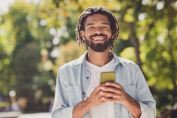 Photo de brune belle peau sombre heureux jeune homme tenir smartphone week-end parc de la ville en plein air — Photo