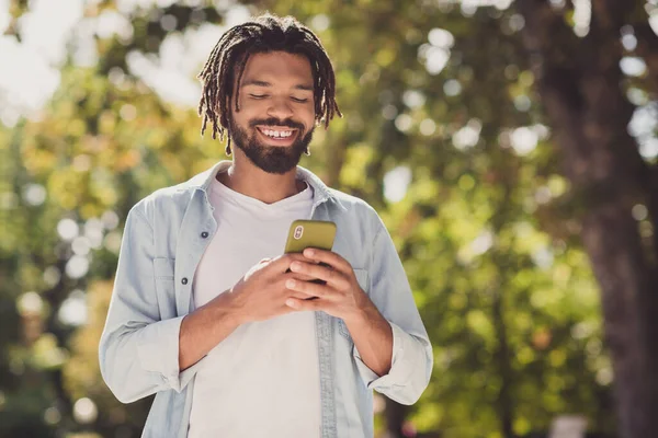 Retrato fotográfico del estudiante en traje casual navegando por Internet con teléfono celular sonriendo caminando por el parque — Foto de Stock