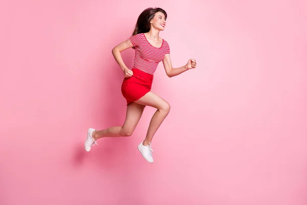 Full storlek profil sida foto av unga attraktiva leende positiv flicka hoppa springa snabbt ser copyspace isolerad på rosa färg bakgrund — Stockfoto