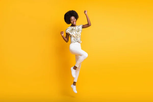 Foto de tamaño completo de optimista hooray señora saltando vestido camiseta zapatillas pantalones aislados sobre fondo amarillo —  Fotos de Stock