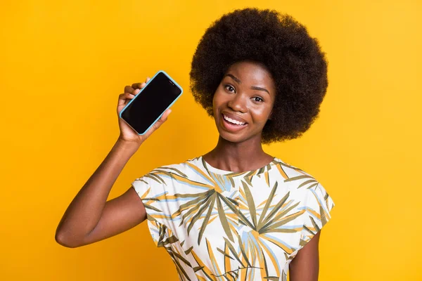 Portret van mooie mooi krullend haar dame met telefoon slijtage print t-shirt geïsoleerd over gele kleur achtergrond — Stockfoto