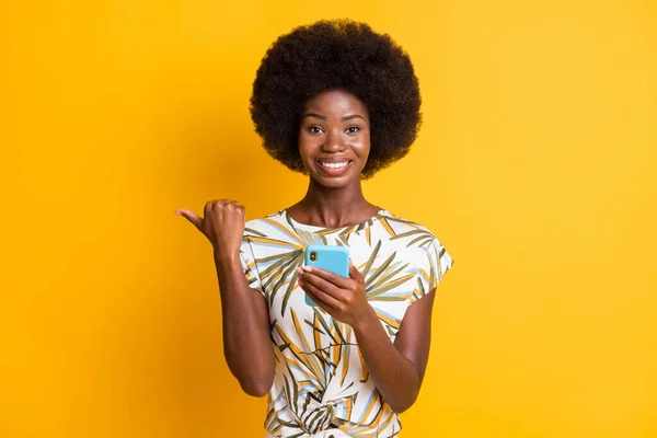Fotografie optimistické pěkné kudrnaté vlasy dáma psaní telefonní bod prázdný prostor oblečení tisk tričko izolované přes živé žluté barvy pozadí — Stock fotografie