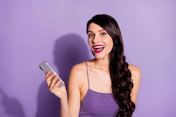 Фото молодой веселой девушки счастливой позитивной улыбкой использовать мобильный телефон изолированы на фиолетовом фоне цвета — стоковое фото